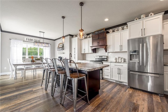 4801 358th St, Stanley, WI 54768 - kitchen with stainless steel appliances, decorative backsplash, a kitchen breakfast bar, dark wood-style flooring, and an island with sink