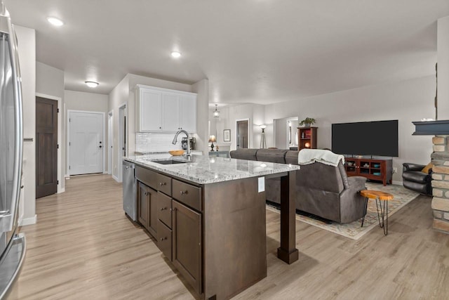 N9225 Constellation Dr, Appleton, WI 54915 - kitchen featuring open floor plan, white cabinets, light wood finished floors, a kitchen bar, and an island with sink