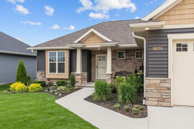 N9225 Constellation Dr, Appleton, WI 54915 - doorway to property featuring stone siding, a garage, roof with shingles, a yard, and covered porch