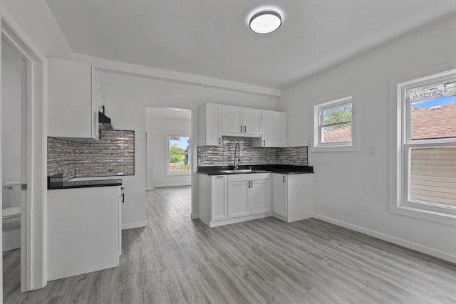 3425 N 20th St, Milwaukee, WI 53206 - kitchen with dark countertops, decorative backsplash, white cabinetry, and healthy amount of natural light