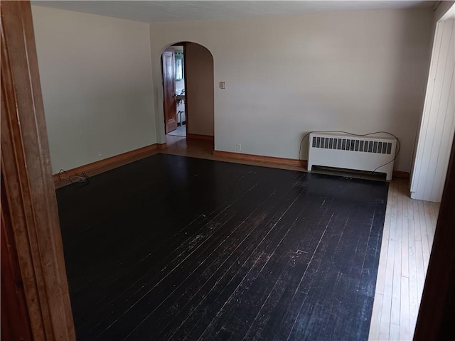 102 E College Ave, Ladysmith, WI 54848 - spare room with hardwood / wood-style flooring, arched walkways, and radiator heating unit