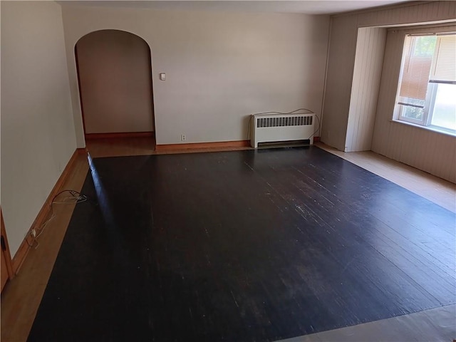 102 E College Ave, Ladysmith, WI 54848 - spare room featuring radiator heating unit, wood finished floors, and arched walkways