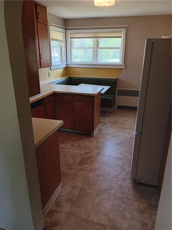 102 E College Ave, Ladysmith, WI 54848 - kitchen with freestanding refrigerator, radiator heating unit, and light countertops