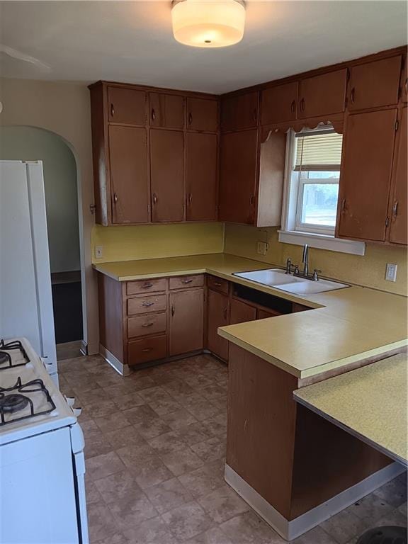 102 E College Ave, Ladysmith, WI 54848 - kitchen with white range with gas cooktop, a peninsula, light countertops, and arched walkways