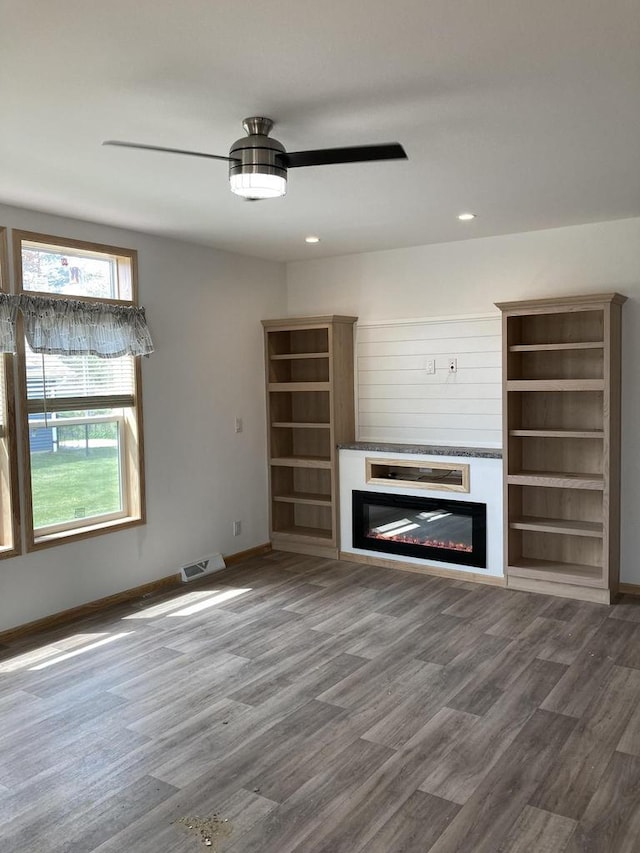 501 View St, Tomah, WI 54660 - unfurnished living room featuring a glass covered fireplace, a ceiling fan, wood finished floors, and recessed lighting