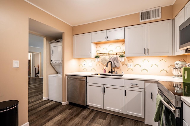 1906 E Shorewood Blvd Unit 250, Shorewood, WI 53211 - kitchen featuring appliances with stainless steel finishes, stacked washing machine and dryer, dark wood-style flooring, white cabinetry, and ornamental molding