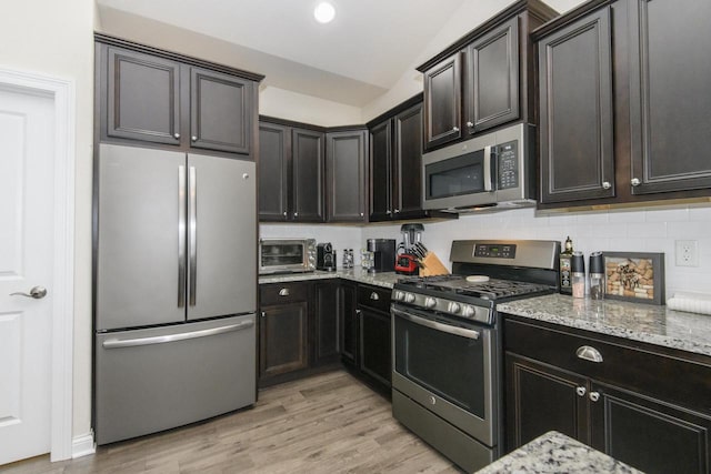 12907 78th Pl, Bristol, WI 53104 - kitchen featuring stainless steel appliances, light stone countertops, lofted ceiling, decorative backsplash, and light wood-style flooring