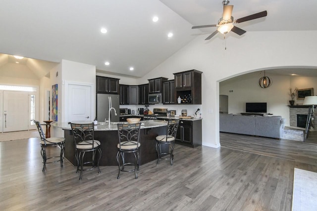 12907 78th Pl, Bristol, WI 53104 - kitchen featuring appliances with stainless steel finishes, open floor plan, high vaulted ceiling, a kitchen bar, and arched walkways