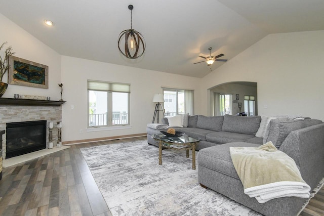 12907 78th Pl, Bristol, WI 53104 - living area with lofted ceiling, ceiling fan, dark wood-style flooring, a stone fireplace, and arched walkways