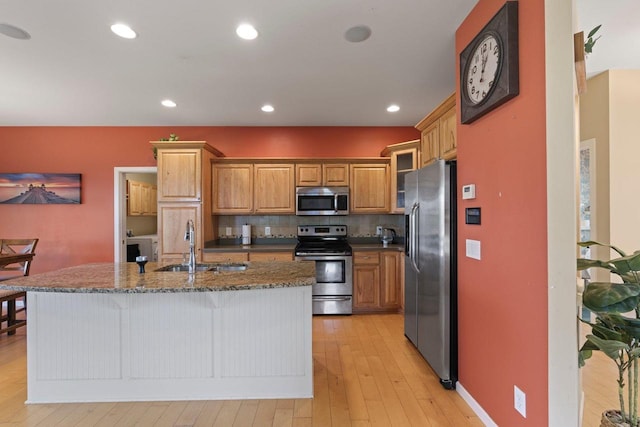 9414 Harvest Moon Ln, Verona, WI 53593 - kitchen with stainless steel appliances, tasteful backsplash, light wood-type flooring, an island with sink, and brown cabinetry