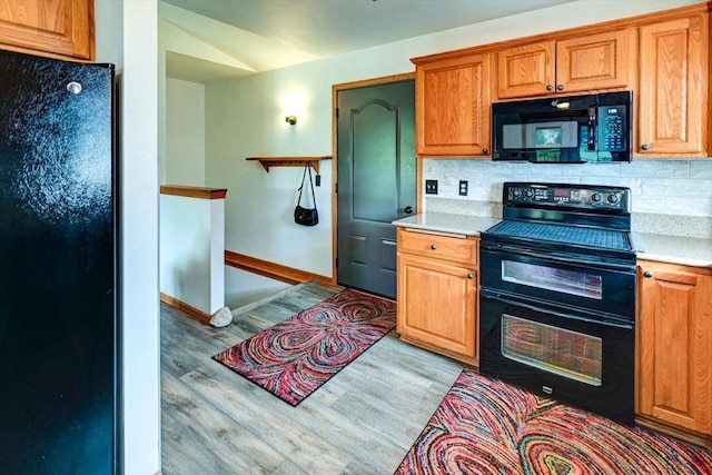 830 Violet Ln, Oregon, WI 53575 - kitchen featuring black appliances, light wood-type flooring, light countertops, and decorative backsplash