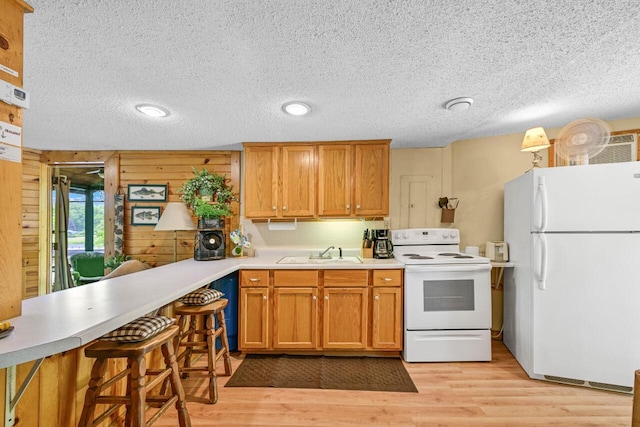 9034 N County Road F, Edgerton, WI 53534 - kitchen featuring white appliances, light countertops, light wood-style flooring, a textured ceiling, and brown cabinetry