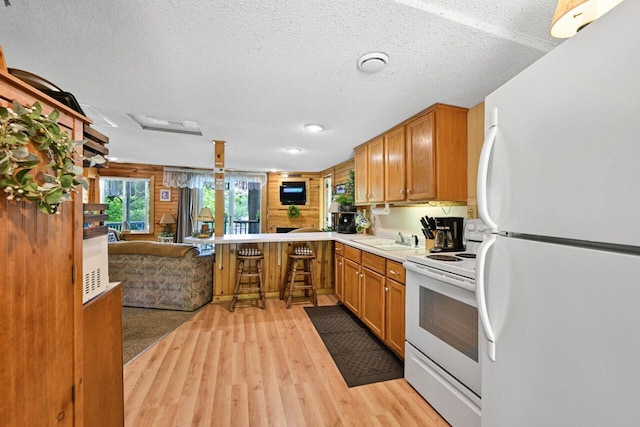 9034 N County Road F, Edgerton, WI 53534 - kitchen with white appliances, open floor plan, light wood-type flooring, a textured ceiling, and brown cabinets