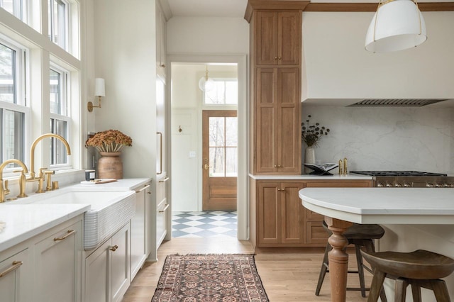 545 Wisconsin Ave, Delafield, WI 53018 - kitchen featuring decorative backsplash, light countertops, a kitchen breakfast bar, stainless steel gas cooktop, and light flooring