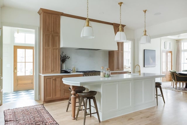 545 Wisconsin Ave, Delafield, WI 53018 - kitchen with light countertops, a breakfast bar area, an island with sink, decorative backsplash, and light flooring