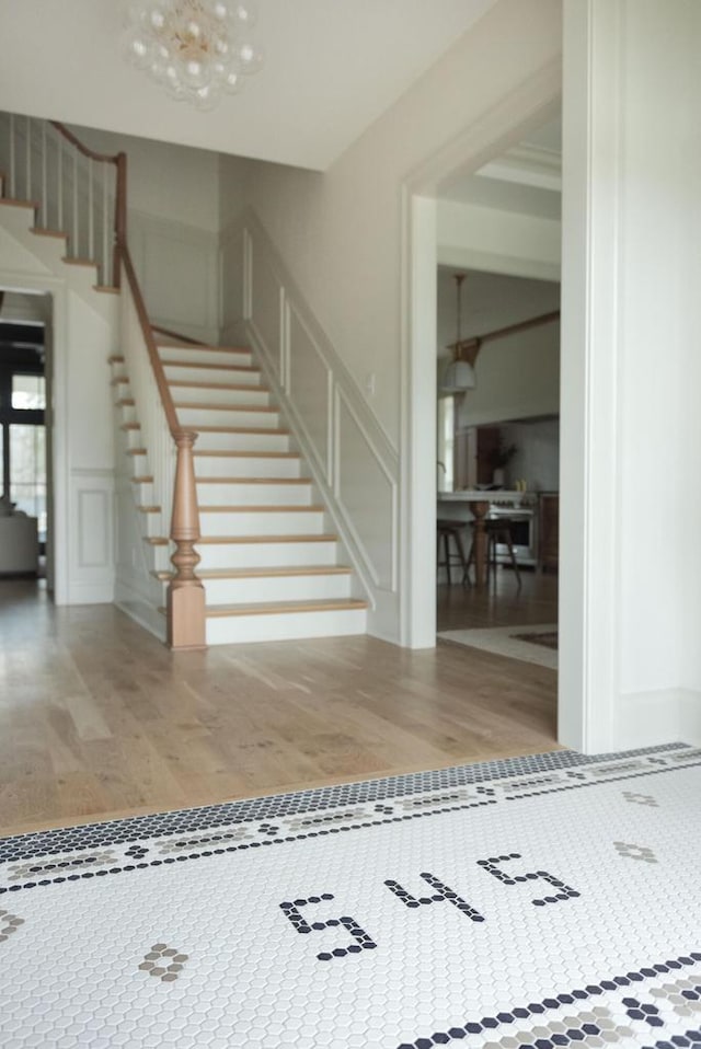 545 Wisconsin Ave, Delafield, WI 53018 - stairs featuring wood finished floors, a decorative wall, and a chandelier