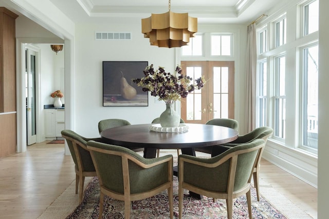 545 Wisconsin Ave, Delafield, WI 53018 - dining space with a chandelier, light wood-style floors, a raised ceiling, and crown molding