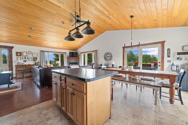 7684 E Moose Lake Rd, Solon Springs, WI 54873 - kitchen featuring wooden ceiling, lofted ceiling, dark countertops, a center island, and a warm lit fireplace