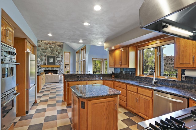 1434 43rd Ave, Kenosha, WI 53144 - kitchen featuring light floors, a stone fireplace, a peninsula, exhaust hood, and appliances with stainless steel finishes