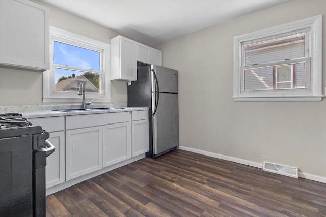 1933 Jay Eye See Ave, Racine, WI 53403 - kitchen with freestanding refrigerator, gas range, dark wood-style flooring, white cabinets, and light countertops