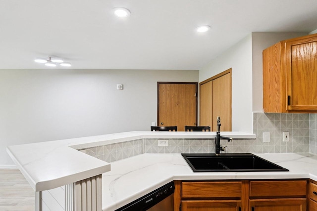 33A Grand Canyon Dr Unit 110, Baraboo, WI 53913 - kitchen featuring dishwasher, a peninsula, tasteful backsplash, light stone countertops, and brown cabinets