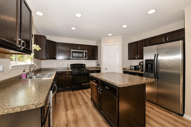 1557 Serena Ln, Burlington, WI 53105 - kitchen featuring appliances with stainless steel finishes, dark brown cabinetry, light wood-style floors, a kitchen island, and recessed lighting
