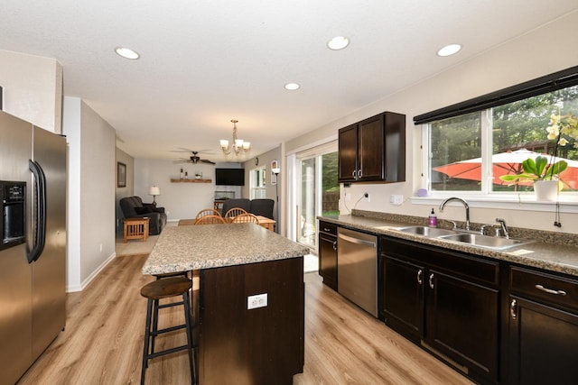 1557 Serena Ln, Burlington, WI 53105 - kitchen with appliances with stainless steel finishes, a kitchen island, a breakfast bar, light wood finished floors, and open floor plan