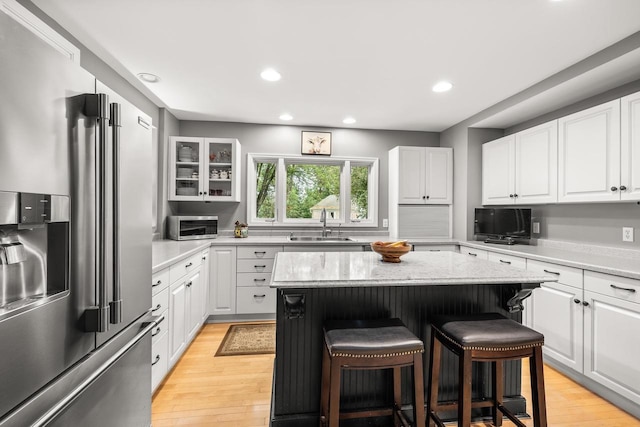 544 Maple Bluff Rd, Stevens Point, WI 54482 - kitchen with high end refrigerator, a breakfast bar area, a kitchen island, white cabinets, and light wood-style flooring