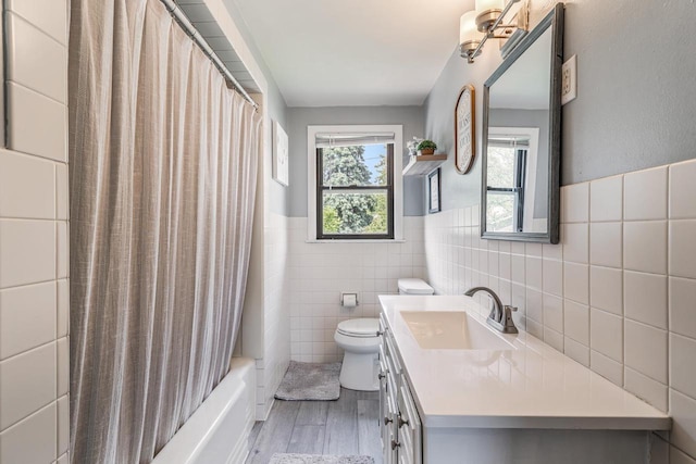 973 Grove St, Neenah, WI 54956 - bathroom featuring tile walls, vanity, wood finished floors, shower / bath combination with curtain, and a wainscoted wall