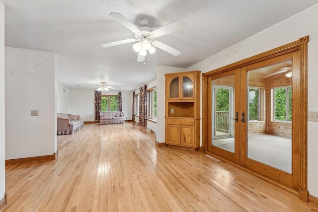 N3045 Lakeview Dr, Montello, WI 53949 - unfurnished living room featuring light wood finished floors, a textured ceiling, plenty of natural light, french doors, and a ceiling fan
