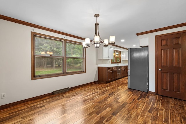 535 Maple Bluff Rd, Stevens Point, WI 54482 - kitchen with freestanding refrigerator, a chandelier, light countertops, crown molding, and dark wood-type flooring