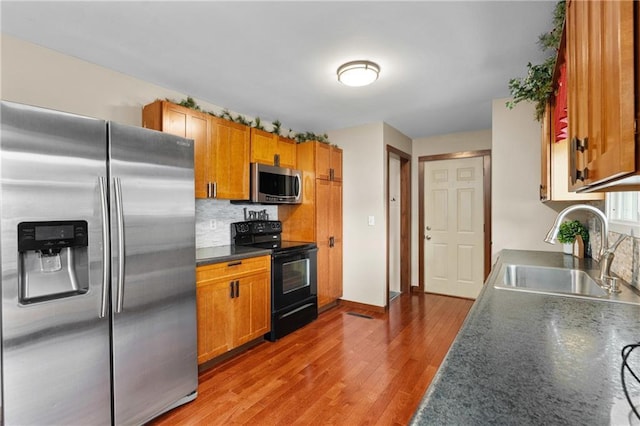1516 Mitscher Ave, Eau Claire, WI 54701 - kitchen featuring stainless steel appliances, light wood finished floors, tasteful backsplash, dark countertops, and brown cabinets