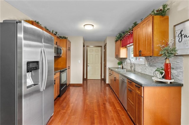 1516 Mitscher Ave, Eau Claire, WI 54701 - kitchen with appliances with stainless steel finishes, light wood-style floors, brown cabinetry, backsplash, and dark countertops