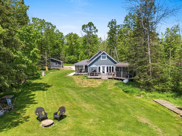 9071 Doemel Ln, Pickerel, WI 54465 - rear view of house with a deck, a sunroom, a lawn, a view of trees, and an outdoor fire pit