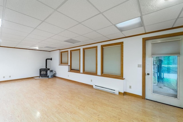 1705 Stark St, Wausau, WI 54403 - below grade area with a wood stove, baseboard heating, light wood-type flooring, and a drop ceiling