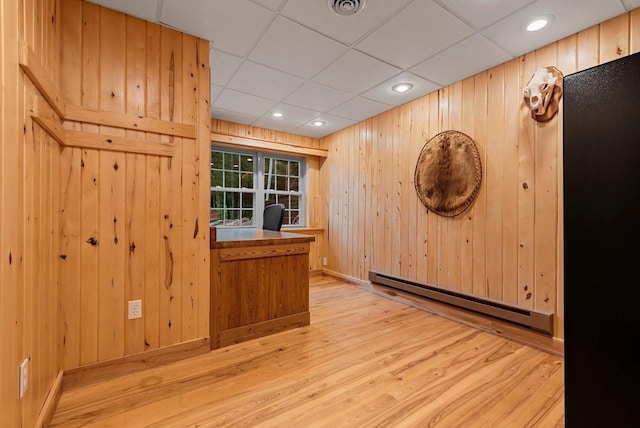 N5730 Parkway Rd, Pound, WI 54161 - unfurnished room with a baseboard radiator, wood finished floors, wood walls, a paneled ceiling, and a desk
