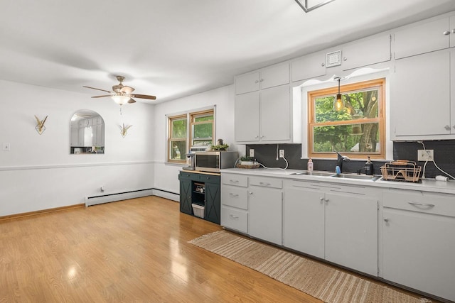 551 Market Ave, Port Edwards, WI 54469 - kitchen with a baseboard heating unit, decorative backsplash, a ceiling fan, light countertops, and light wood-type flooring