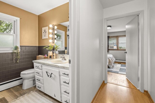 551 Market Ave, Port Edwards, WI 54469 - ensuite bathroom with wood finished floors, vanity, plenty of natural light, tile walls, and baseboard heating