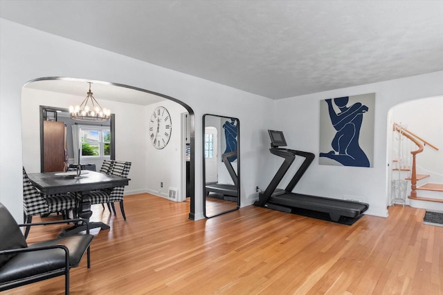6738 W Monona Pl, West Allis, WI 53219 - exercise area featuring arched walkways, light wood-style flooring, and a chandelier