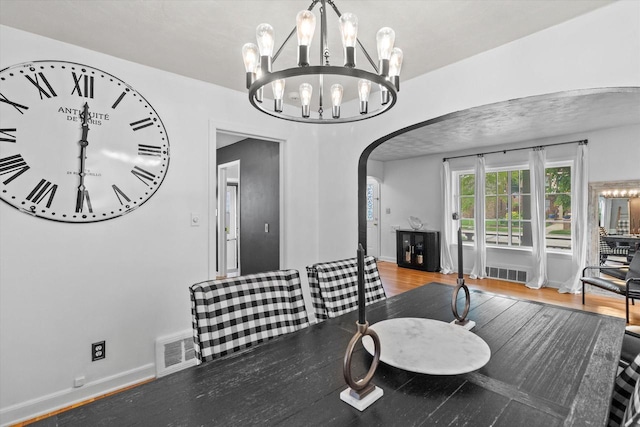 6738 W Monona Pl, West Allis, WI 53219 - dining space with arched walkways, a chandelier, and wood finished floors