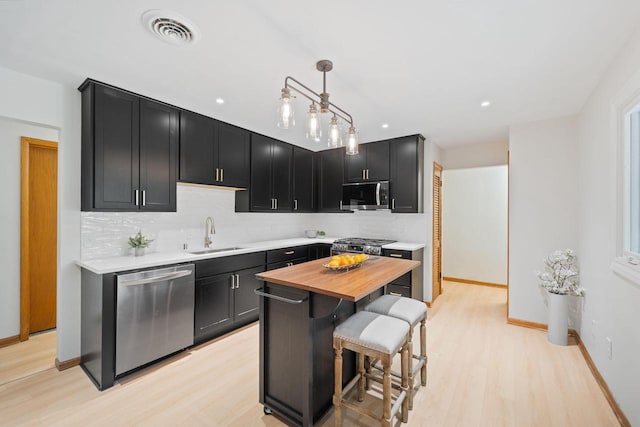 4326 Taylor Ave, Mount Pleasant, WI 53405 - kitchen with stainless steel appliances, butcher block counters, light wood-style flooring, dark cabinets, and backsplash