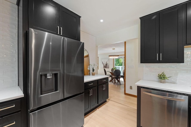 4326 Taylor Ave, Mount Pleasant, WI 53405 - kitchen featuring appliances with stainless steel finishes, dark cabinets, light wood-style flooring, tasteful backsplash, and light countertops