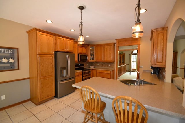 551 Bayberry Ln, Slinger, WI 53086 - kitchen featuring stainless steel appliances, arched walkways, a peninsula, glass insert cabinets, and pendant lighting