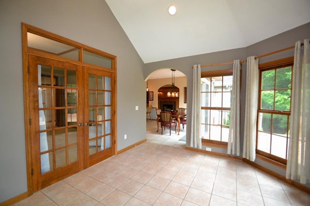 551 Bayberry Ln, Slinger, WI 53086 - unfurnished room with arched walkways, french doors, light tile patterned flooring, high vaulted ceiling, and a fireplace