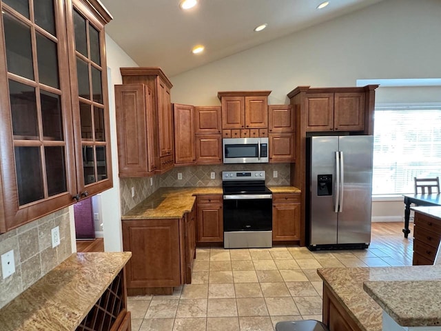 4126 Westerfield Ln, Madison, WI 53704 - kitchen with appliances with stainless steel finishes, brown cabinets, lofted ceiling, tasteful backsplash, and glass insert cabinets