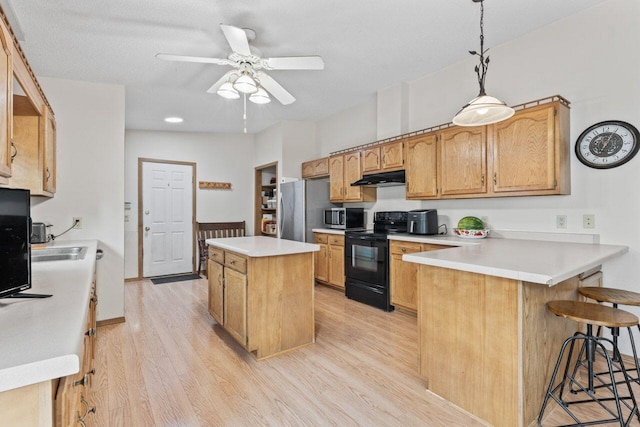 12129 221st Ave, Bristol, WI 53104 - kitchen with stainless steel appliances, under cabinet range hood, light wood-type flooring, a peninsula, and a center island