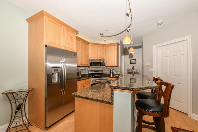 1515 N Van Buren St Unit 414, Milwaukee, WI 53202 - kitchen with appliances with stainless steel finishes, light brown cabinetry, light wood finished floors, decorative backsplash, and a breakfast bar