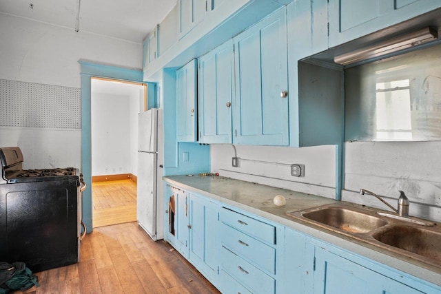 1049 E Johnson St, Madison, WI 53703 - kitchen with stove, freestanding refrigerator, blue cabinets, light wood-type flooring, and wallpapered walls