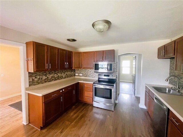 628 W Cedar St, Chippewa Falls, WI 54729 - kitchen with appliances with stainless steel finishes, light countertops, tasteful backsplash, arched walkways, and dark wood-type flooring