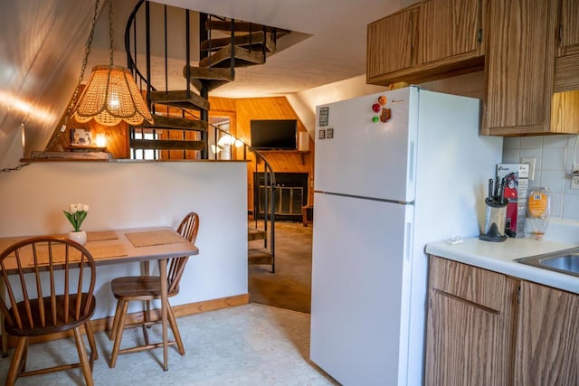 N8244 Woodland Trl, New Lisbon, WI 53950 - kitchen featuring freestanding refrigerator, light countertops, light floors, brown cabinets, and decorative backsplash